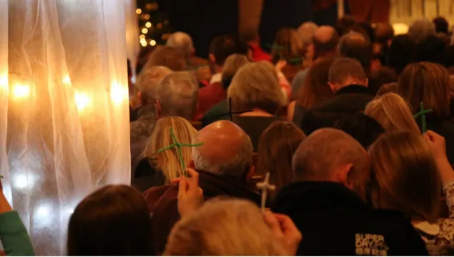 photo of people holding pipe cleaner crosses during church service